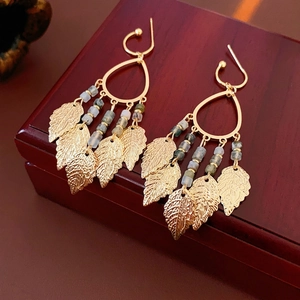 Golden water drop leaf tassel earrings with beads on a red wooden jewelry box