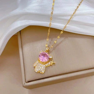 Titanium steel gold bear necklace with pink zircon and diamonds on beige jewelry box