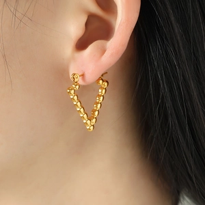 Minimalist gold beaded V-shaped earrings worn by a model showcasing high-end fashion jewelry