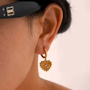 Golden heart drop earrings with evil eye zircon inlay shown on fashion model