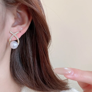 Close-up of elegant gold pearl drop earrings with sparkling diamonds on female model