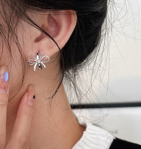 Macro shot of a polished silver bow-shaped hoop earring worn on a female model