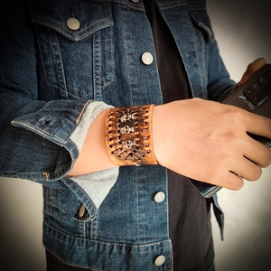Brown vintage wide leather wristband with three metallic skulls and woven stitching details