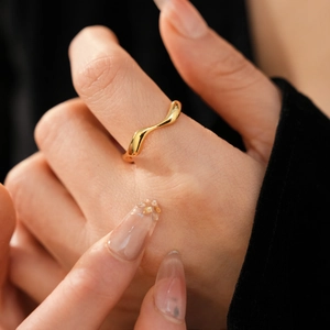Detailed close-up of an 18k gold plated irregular wave ring on a model's finger