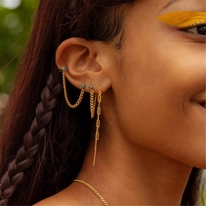 Close-up of gold chain earrings with blue gems and tassels worn by a model