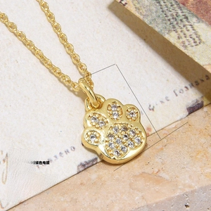 Macro shot of 18k gold plated copper paw print pendant necklace with zircon stones