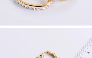 Macro detail of gold C-shaped earrings with clear sparkling rhinestones and size ruler