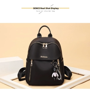 Detail of black waterproof oxford backpack with gold zippers and cute cat pendant