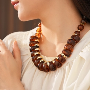 Gros plan d'un collier vintage avec perles en résine marron et anneaux dorés élégants