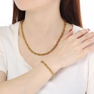 Detail view of a gold-toned twisted rope chain necklace and bracelet set on a model