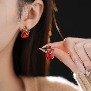 Close-up of vintage silver earrings with red square crystal and metal flower detail