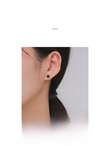 Close-up of minimalist black star stud earring worn on ear for elegant jewelry detail