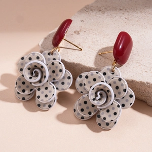 Detailed macro view of layered acrylic floral earrings with retro black polka dots