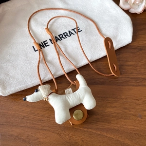 Close-up of white fabric dachshund cable organizer with brown leather strap on wooden desk