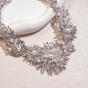 Detail shot of silver coral branch necklace with white pearls on a minimalist background