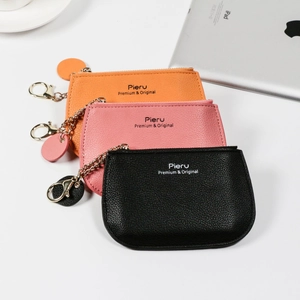 Three minimalist lychee texture coin purses in orange, pink and black with gold keychains