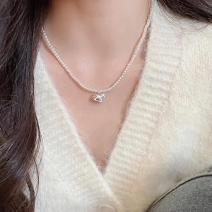 Close-up of pearl necklace featuring a colorful enamel rocking horse pendant on a model
