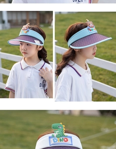 Detailed view of children's visor hats with bear and dino motifs on a sunny lawn