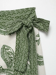 Detailed macro shot of the green and white floral print fabric with a waist bow tie design