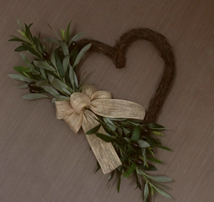 Macro detail of heart-shaped olive wreath featuring rustic twigs and burlap bow