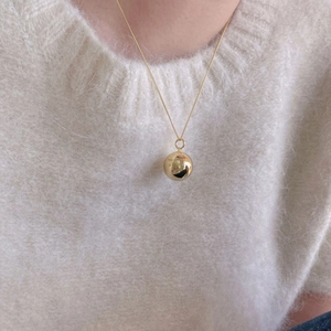 Close-up of golden sphere pendant with You deserve to be loved engraving on a model