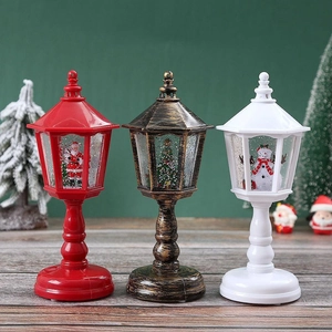 Three Christmas LED lanterns in red, bronze, and white on a rustic wooden table