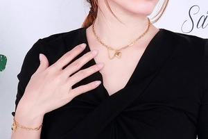 Close-up of a gold heart pendant necklace and matching bracelet set on a model