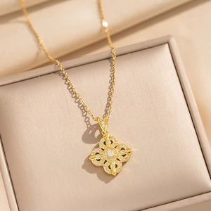 Elegant gold clover pendant necklace with sparkling crystals on silk background