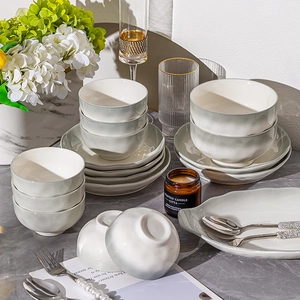 Minimalist green ceramic dinnerware set with wavy edges on a marble surface