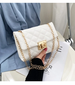 Close-up of white quilted crossbody bag featuring a gold square lock and chain strap