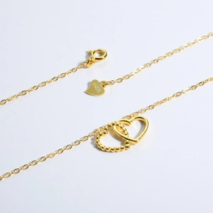 Macro detail of S925 sterling silver stamp on golden interlocking heart necklace