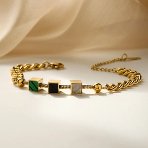 Gold stainless steel chain bracelet with colorful cube shell pendants on silk background