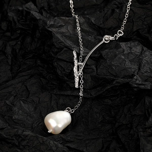 Macro shot of silver branch link and baroque freshwater pearl on black texture background