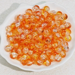 Macro shot of 6mm-8mm orange crackle glass beads in a white shell dish for DIY jewelry