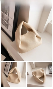 Close-up of cream pleated handbag with lychee pattern leather and knotted handle detail