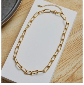 Detail view of golden paperclip chain necklace with adjustable link on display