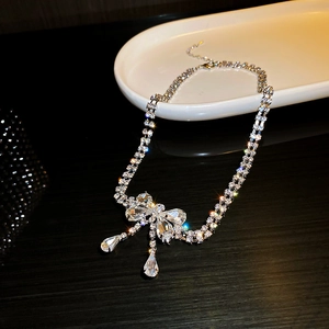 Detail of silver bow necklace with sparkling crystals and elegant teardrop pendants