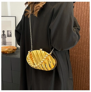 Detailed close-up of golden shell-shaped acrylic evening bag with pearls and chain strap