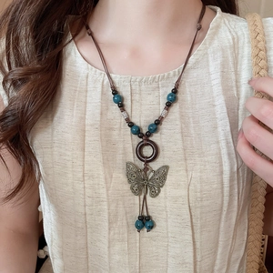 Detail view of ethnic butterfly pendant necklace with wood beads and ceramic accents