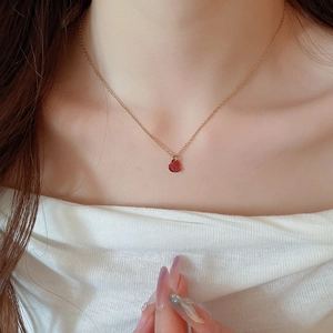 Dettaglio di una collana con ciondolo a cuore rosso dorato indossata sul collo
