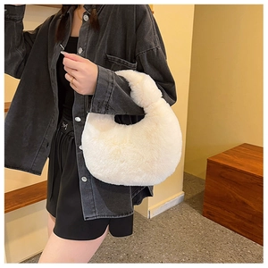 Detailed view of soft white plush dumpling bag worn as a shoulder bag on a model