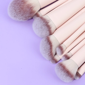 Pink makeup brush set with dual-tone synthetic bristles on a soft purple background