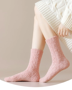 Close-up of pink coral fleece socks showing soft cable knit texture on a model