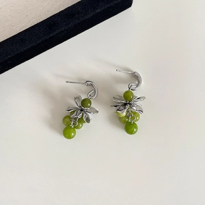 Close-up of C-shaped flower earrings with green jade beads and silver leaves