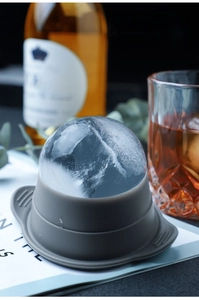 Close-up of a large clear ice ball made with a dark grey silicone sphere mold