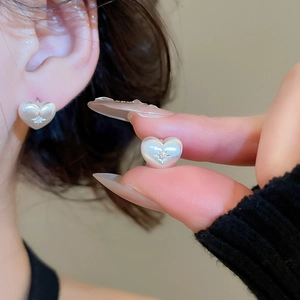 Close-up of heart-shaped earring with pearlescent finish and star-set zircon detail