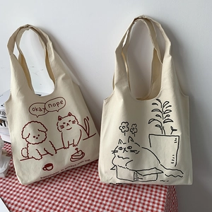 Detail of two beige canvas tote bags with cute pet illustrations on a red checkered tablecloth