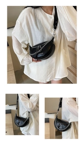 Close-up of black faux leather moon bag with silver chain detail and white branding