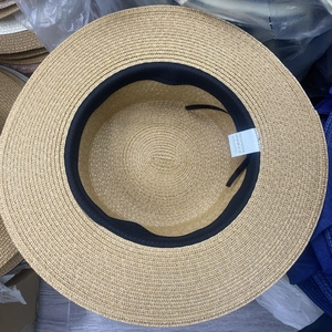 Detail of 100% paper straw hat interior featuring black adjustable ribbon and material tag