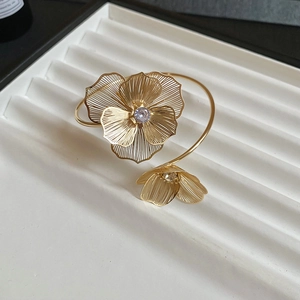 Detailed macro shot of a gold open cuff bracelet with intricate hollow flower designs